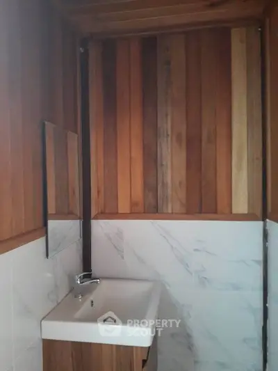 Cozy bathroom with wooden paneling and sleek white sink