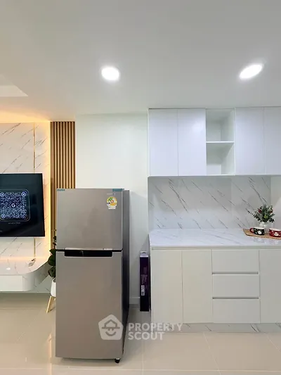 Modern kitchen with sleek white cabinets and stainless steel fridge