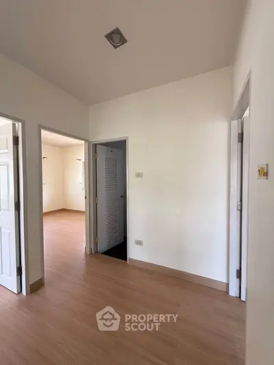 Spacious interior hallway with wooden flooring and multiple doorways in a modern home.