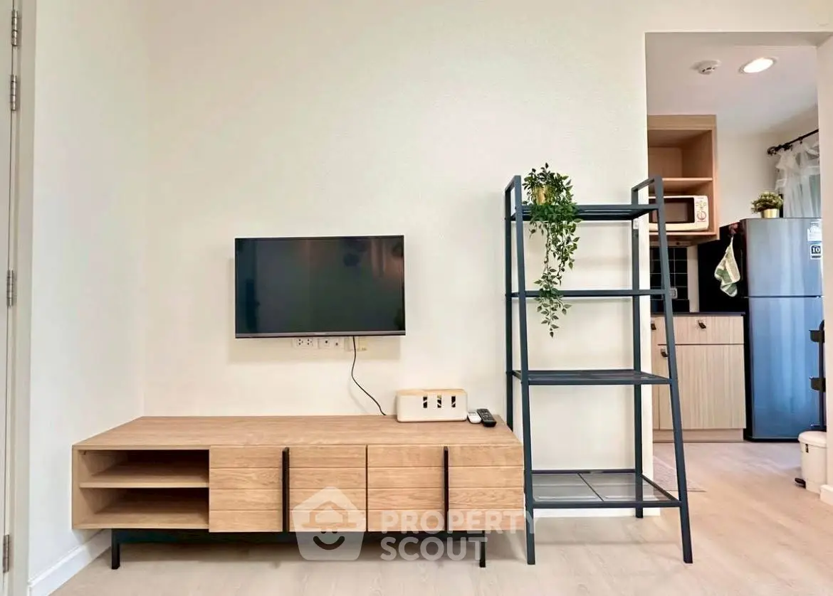 Modern living room with sleek TV stand and open shelving, adjacent to a stylish kitchen area.