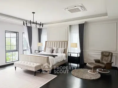 Luxurious bedroom with elegant decor, featuring a plush bed, stylish armchair, and large windows for natural light.