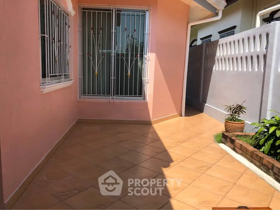 Charming outdoor patio with tiled flooring and decorative window grills, perfect for relaxation.