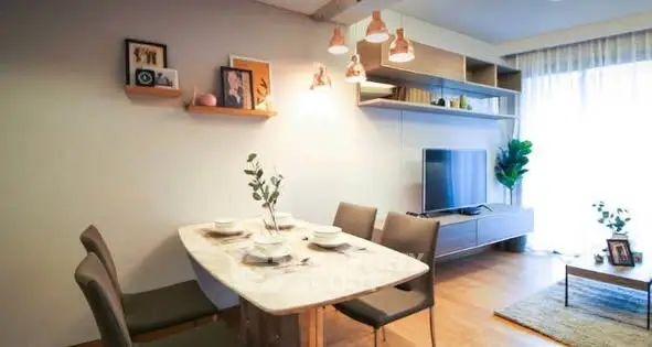 Modern living room with stylish dining area and TV setup, featuring elegant lighting and decor.