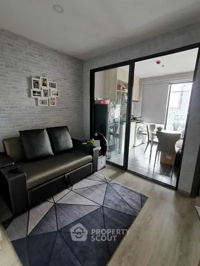 Modern living room with sliding glass doors leading to a stylish kitchen and balcony view.