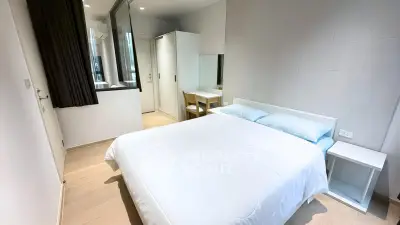 Modern minimalist bedroom with white bedding and sleek furniture in a stylish apartment.