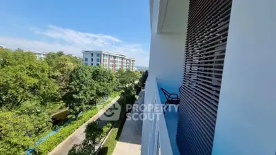 Spacious balcony with scenic view of lush greenery and modern buildings, perfect for relaxation.
