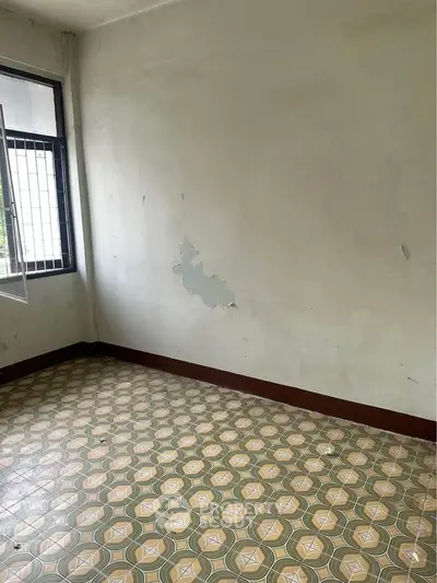 Spacious empty room with vintage patterned floor tiles and natural light from window.