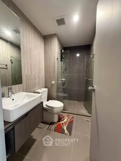 Modern bathroom with sleek design, featuring a glass shower enclosure and stylish fixtures.