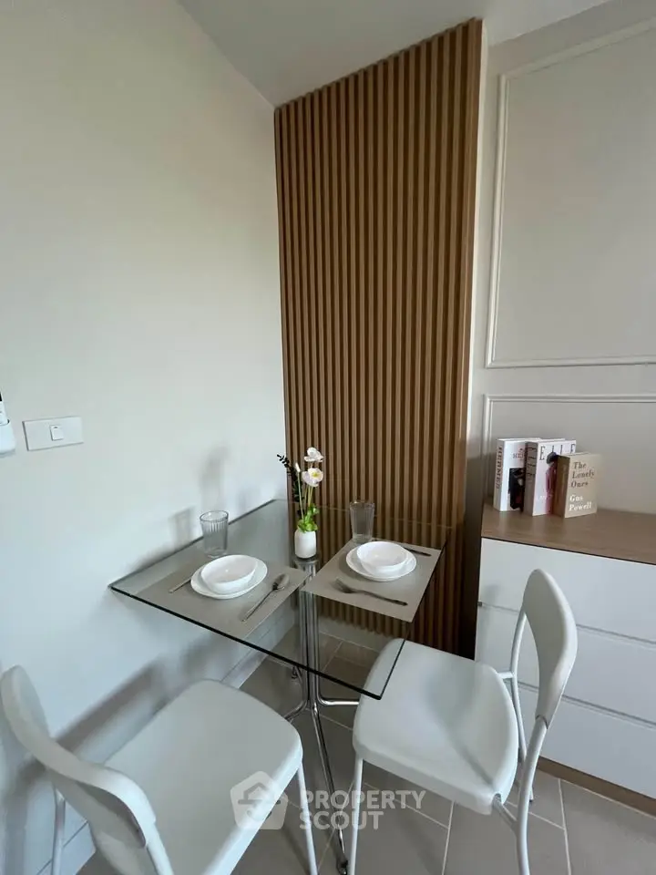 Modern kitchen nook with glass table and sleek white chairs in stylish apartment