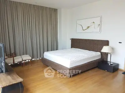 Spacious bedroom with modern decor and large window, featuring a comfortable bed and stylish furnishings.