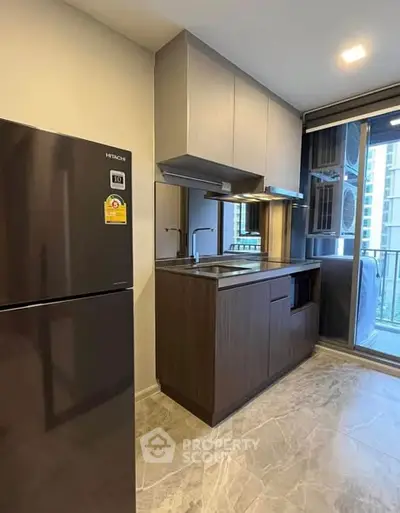 Modern compact kitchen with sleek cabinetry and stainless steel appliances in a high-rise apartment.