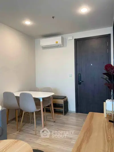 Modern dining area with sleek table and chairs, wooden flooring, and air conditioning in a cozy apartment.
