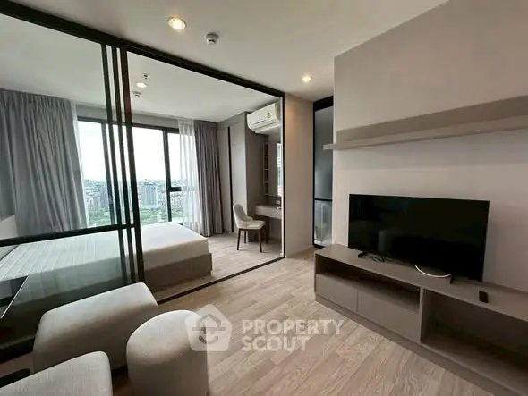 Modern apartment with open living room and bedroom, featuring large windows and stylish decor.