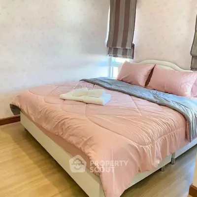 Cozy bedroom with soft pink bedding and natural light, perfect for relaxation.