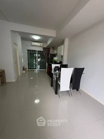 Spacious modern living area with sleek dining set and glossy tiled floors.