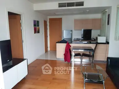 Modern open-layout living room with kitchen, wooden flooring, and stylish furniture.