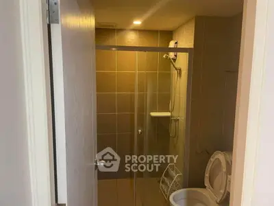 Modern bathroom with glass shower door and tiled walls in a cozy apartment.