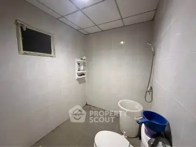 Spacious bathroom with tiled walls and ceiling, featuring a shower and toilet.