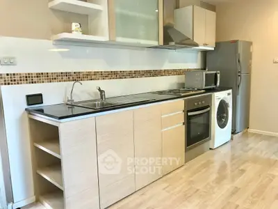 Modern kitchen with sleek cabinetry, stainless steel appliances, and wood flooring.