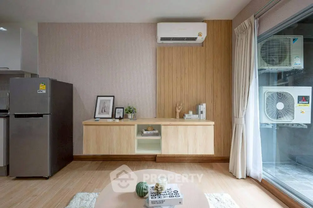 Modern living room with air conditioning and stylish decor, featuring a sleek wooden cabinet and large window.