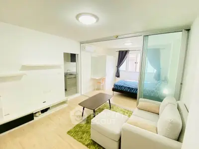 Modern open-plan living room with cozy seating and bedroom view in a stylish apartment.