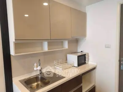 Modern kitchen with sleek cabinetry and built-in microwave in a stylish apartment.