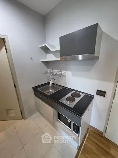 Compact modern kitchen with sleek cabinetry and electric stove in cozy apartment