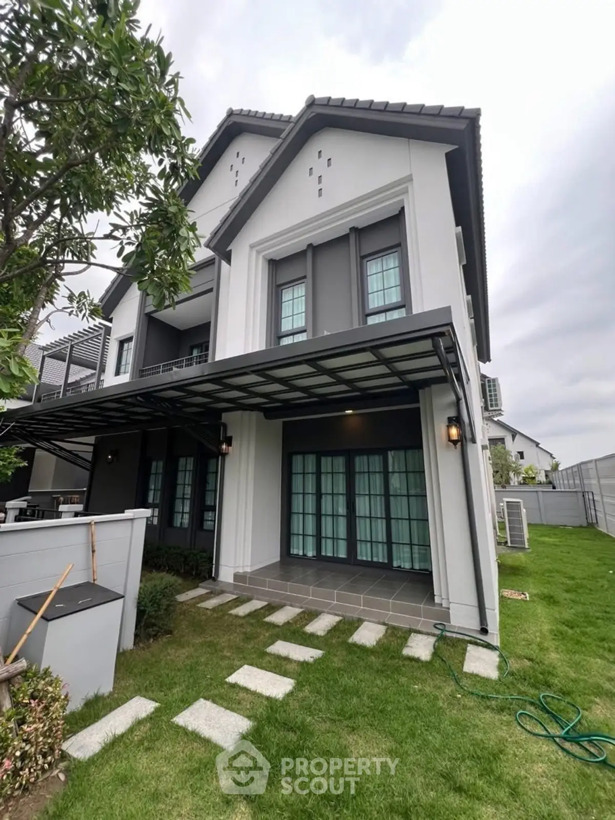 Elegant modern house exterior with lush green lawn and stylish architecture.