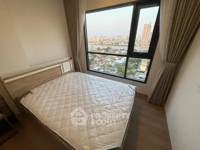 Spacious bedroom with large window offering stunning city view, perfect for urban living.