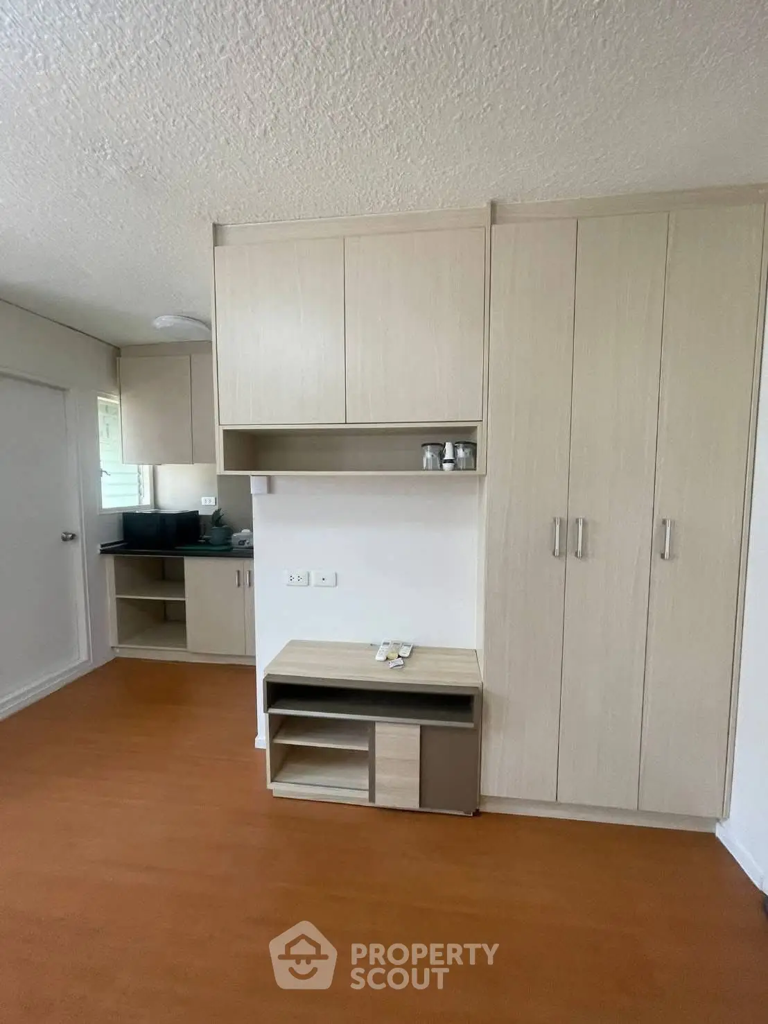 Modern apartment interior with sleek storage cabinets and warm wooden flooring.