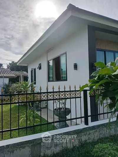 Charming single-story home with lush garden and decorative fence, perfect for serene living.