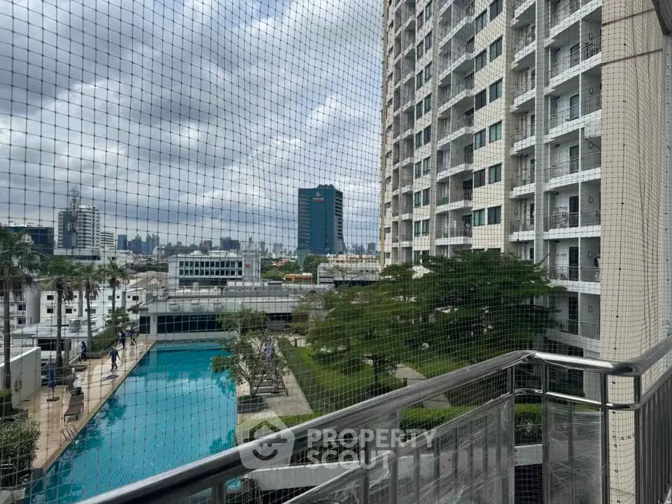 Stunning cityscape view from a high-rise balcony overlooking a luxurious pool and modern building.