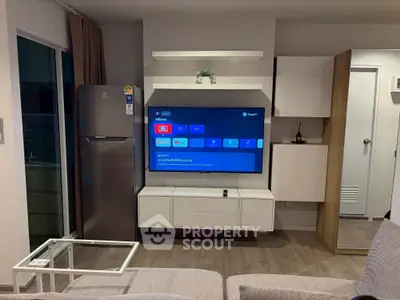 Modern living room with sleek TV setup and stainless steel fridge, perfect for contemporary urban living.
