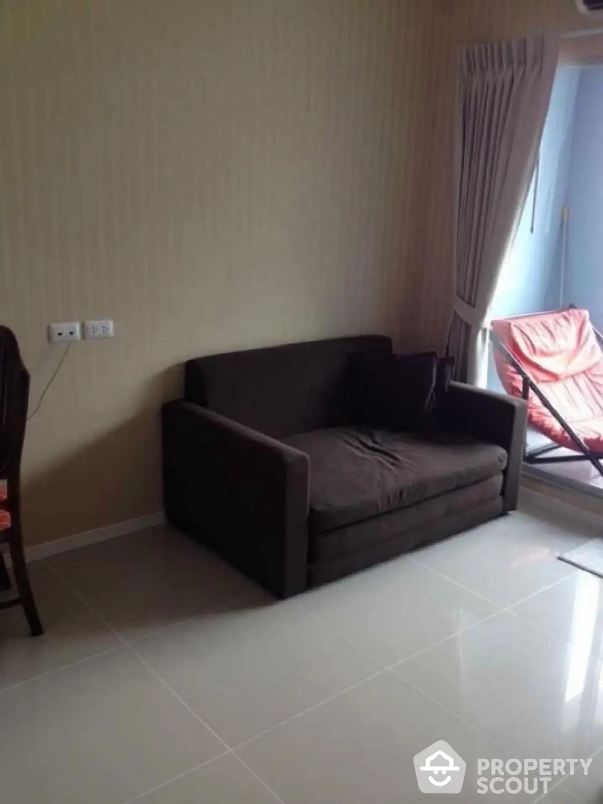 Cozy living room with dark sofa and natural light from window