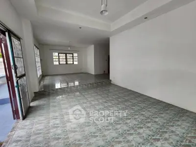 Spacious open-plan living area with tiled flooring and large windows for natural light.