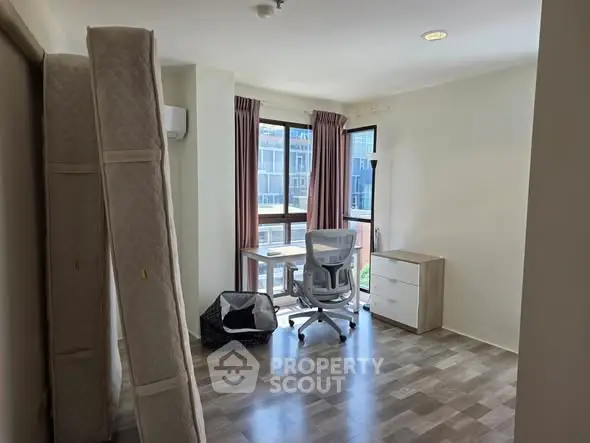 Bright study room with modern chair and desk, large windows, and wooden flooring.