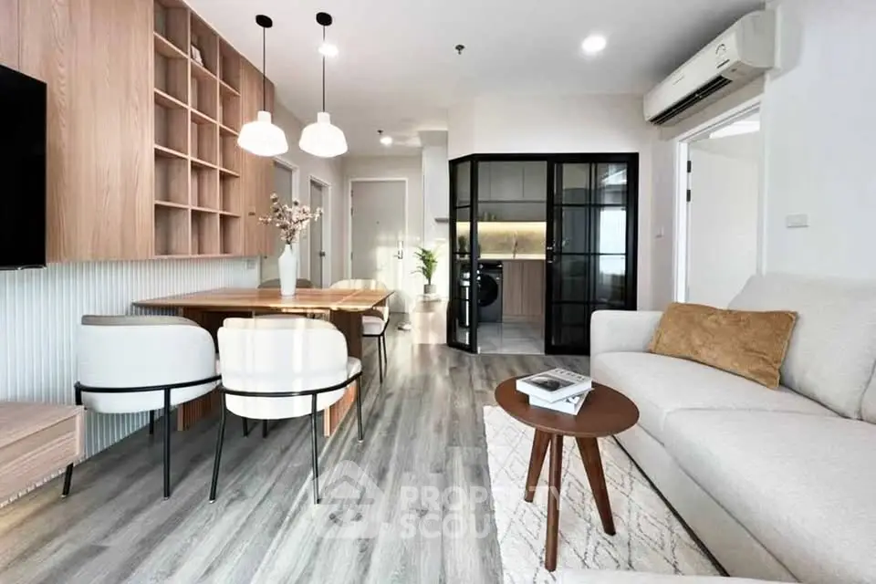 Modern living room with stylish furniture and open layout, featuring a cozy dining area and sleek wooden accents.