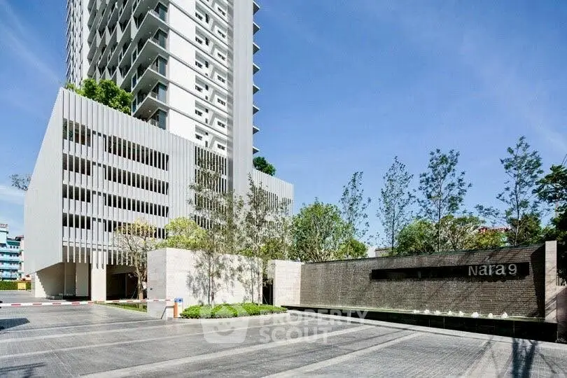 Modern high-rise building with sleek architecture and landscaped entrance in urban setting.