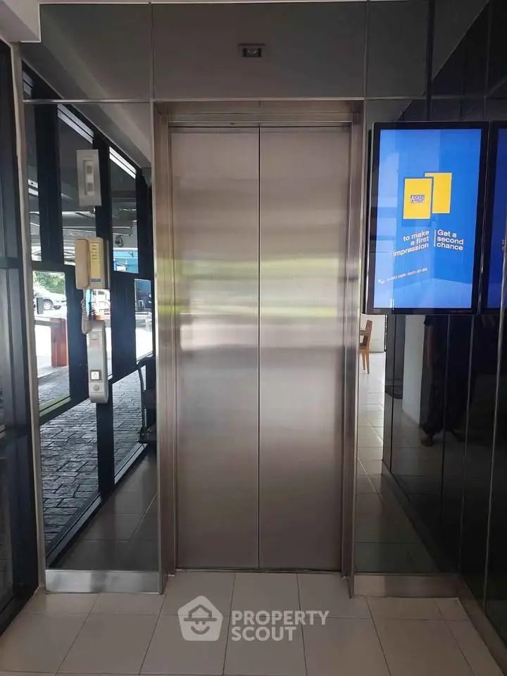Modern building elevator with sleek design and digital display in lobby area.