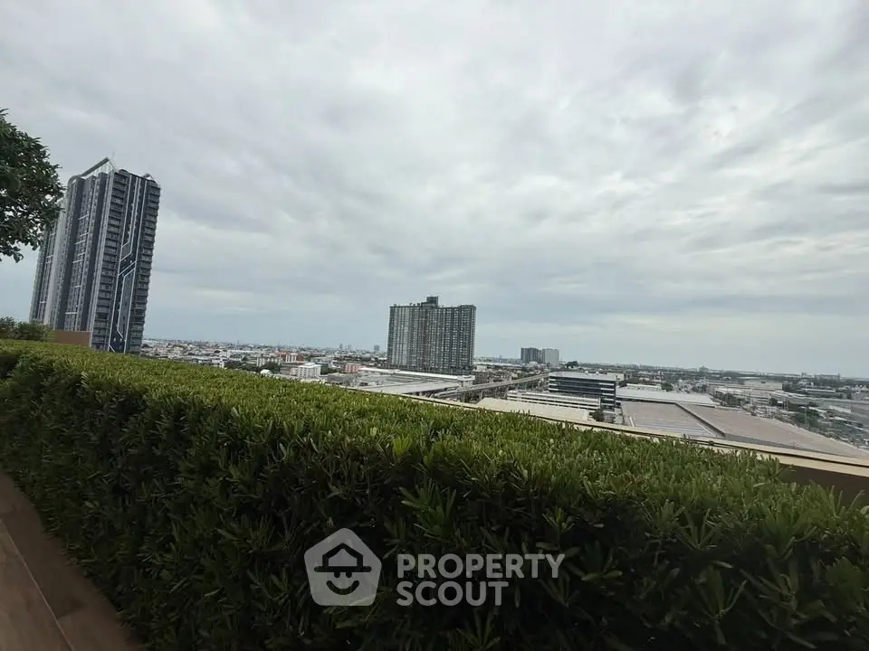 Stunning cityscape view from a lush rooftop garden, showcasing modern high-rise buildings under a cloudy sky.