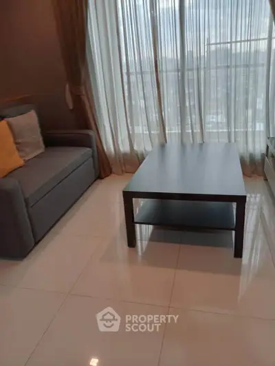 Modern living room with sleek sofa and coffee table, featuring floor-to-ceiling windows for natural light.
