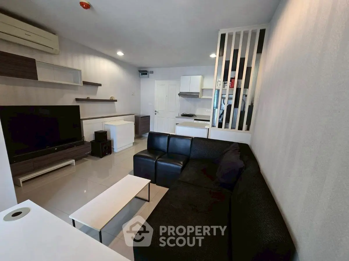 Modern living room with sleek black sofa and open kitchen layout