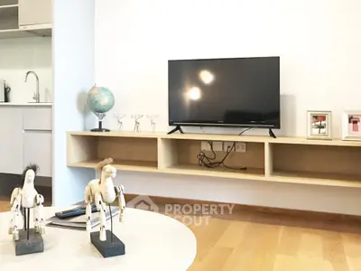 Modern living room with mounted TV, wooden flooring, and stylish decor