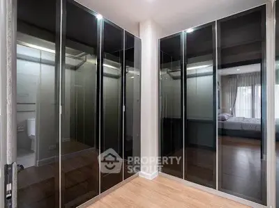 Spacious bedroom with sleek mirrored wardrobes and modern design.