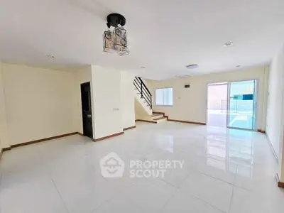 Spacious open-plan living room with modern staircase and large windows