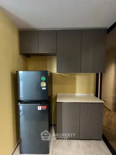 Modern kitchen with sleek cabinets and stainless steel fridge in a compact layout.