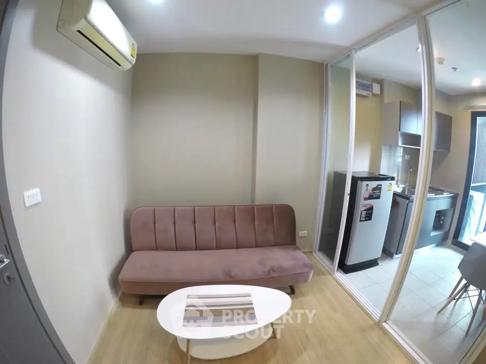 Modern living room with sleek design and compact kitchen area, featuring a cozy sofa and stylish coffee table.