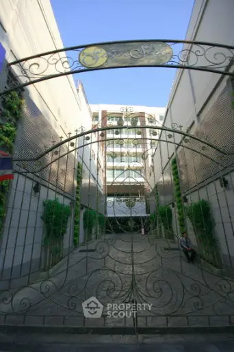 Elegant gated entrance with intricate ironwork leading to a modern building.