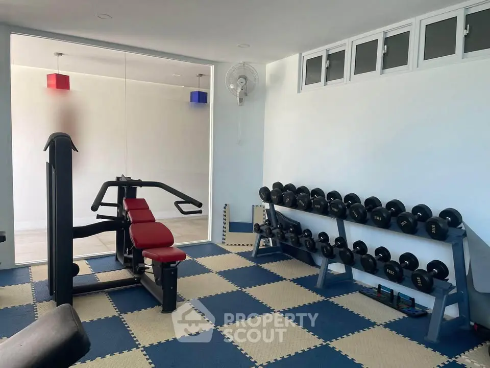 Modern gym with weights and exercise equipment in a residential building.