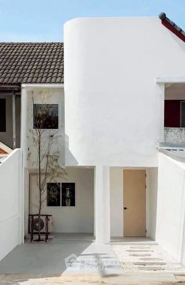 Modern minimalist white townhouse exterior with unique curved facade and clean lines.